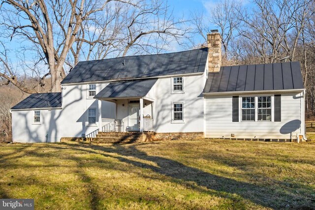  - rear view of property featuring a standing seam roof, a chimney, metal roof, and a yard