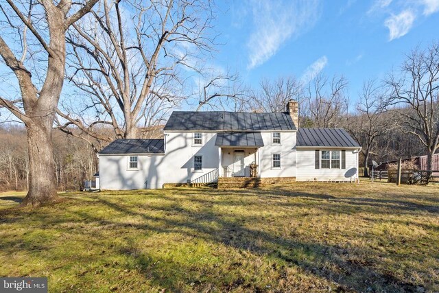  - rear view of property featuring a chimney, a lawn, and metal roof