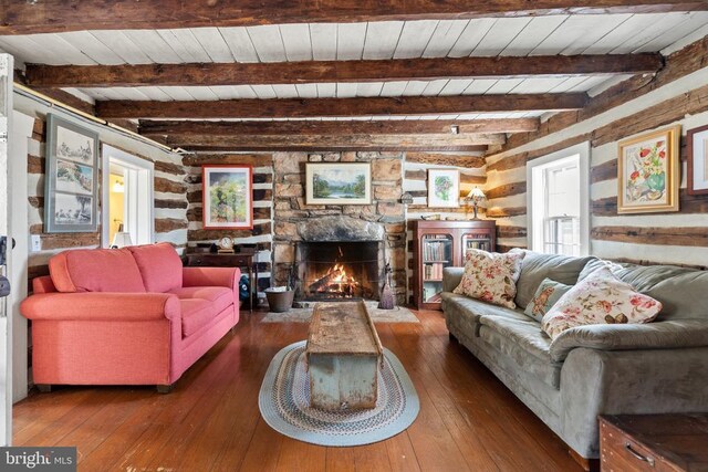  - living area with wood-type flooring, a stone fireplace, and wood ceiling with exposed beams