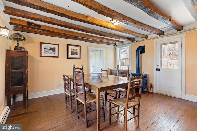  - dining area featuring beamed ceiling, a baseboard radiator, hardwood / wood-style flooring, baseboards, and a wood stove
