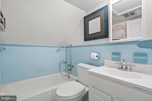  - bathroom featuring vanity, lofted ceiling, toilet, tile walls, and  shower combination