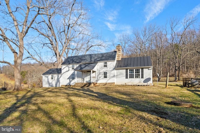  - back of property with a chimney, a lawn, and metal roof