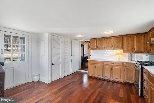  - kitchen featuring stainless steel range with gas stovetop, white microwave, dark wood-style flooring, and light countertops