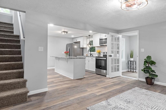 14372 E Side Hwy S, Grottoes, VA 24401 - kitchen featuring appliances with stainless steel finishes, white cabinetry, a breakfast bar, light wood-style floors, and light stone countertops