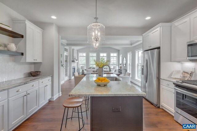 kitchen with a sink, open shelves, open floor plan, stainless steel appliances, and white cabinets