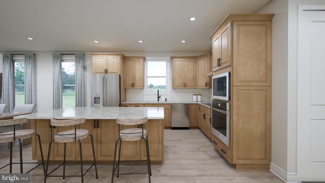 kitchen featuring a sink, decorative backsplash, light brown cabinetry, stainless steel appliances, and a center island