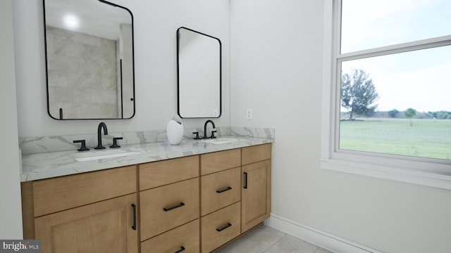 bathroom featuring tile patterned flooring, double vanity, baseboards, and a sink