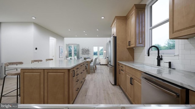 kitchen with a wealth of natural light, a kitchen island, stainless steel appliances, and a sink