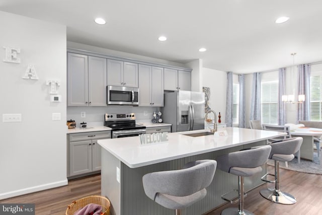 3801 Drayton Ct, Fredericksburg, VA 22408 - kitchen with appliances with stainless steel finishes, gray cabinetry, wood finished floors, a kitchen breakfast bar, and a kitchen island with sink