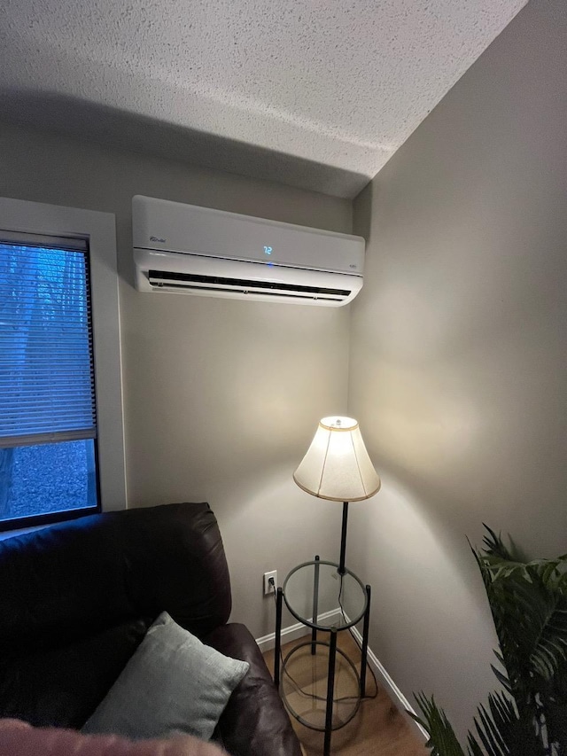 sitting room featuring baseboards, a textured ceiling, and an AC wall unit