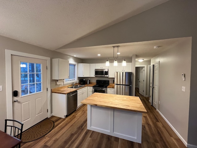 kitchen with a sink, butcher block counters, dark wood-style flooring, white cabinets, and appliances with stainless steel finishes