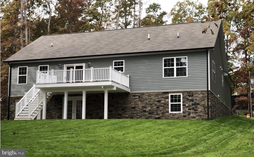 back of property with french doors, a deck, stone siding, and a yard