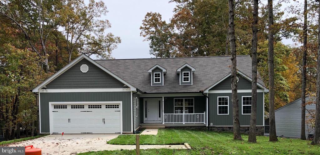 view of front facade featuring a porch, an attached garage, concrete driveway, a front lawn, and a shingled roof