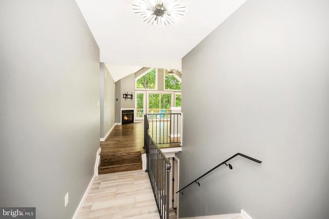 14906 Laurel Point Ln, Spotsylvania, VA 22551 - stairway featuring vaulted ceiling, wood finished floors, a chandelier, and a lit fireplace