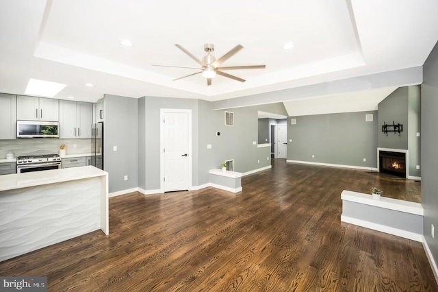 14906 Laurel Point Ln, Spotsylvania, VA 22551 - unfurnished living room with a tray ceiling, a ceiling fan, a lit fireplace, dark wood-type flooring, and recessed lighting