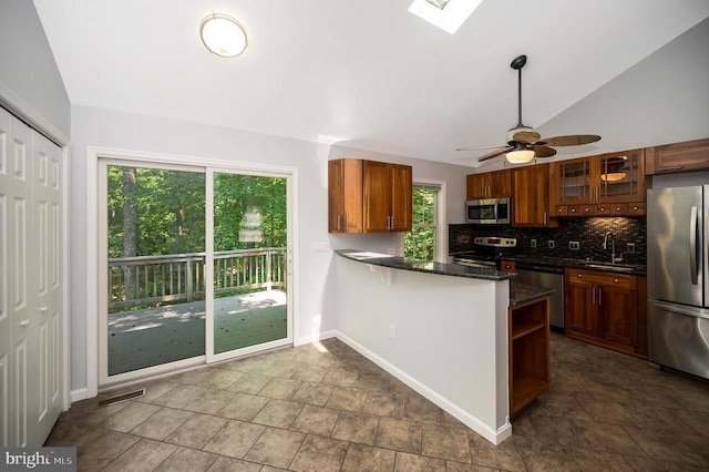 14906 Laurel Point Ln, Spotsylvania, VA 22551 - kitchen with appliances with stainless steel finishes, vaulted ceiling, dark stone finish flooring, backsplash, and a peninsula