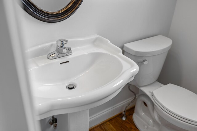 half bath featuring toilet, a sink, and wood finished floors
