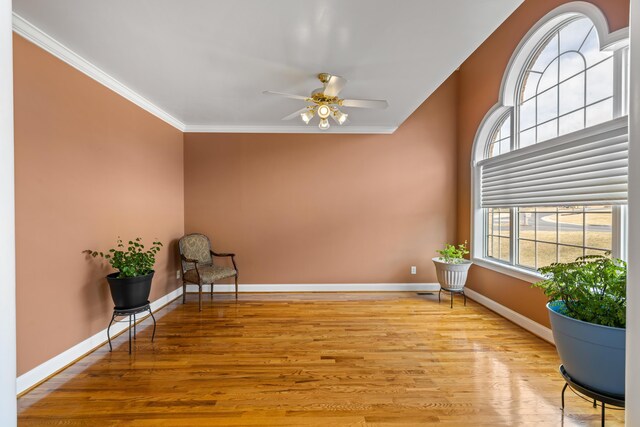 living area featuring crown molding, baseboards, ceiling fan, and wood finished floors