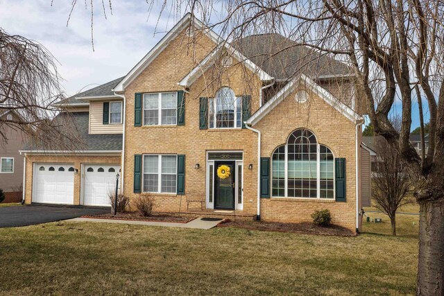 view of front of house with driveway, a shingled roof, brick siding, and a front yard