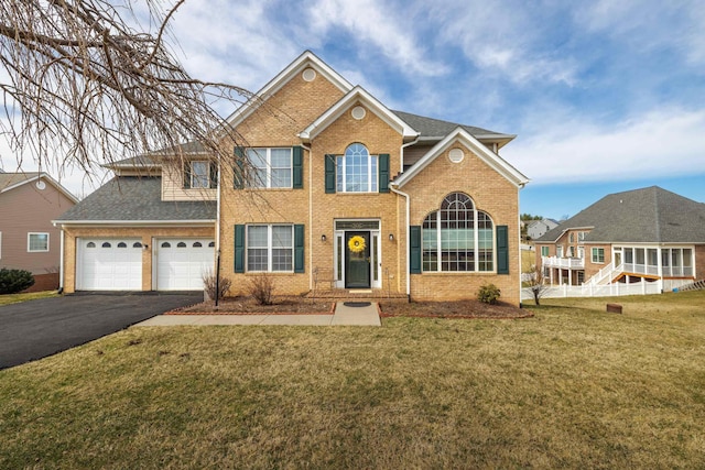 view of front of home featuring a garage, a front lawn, roof with shingles, brick siding, and driveway