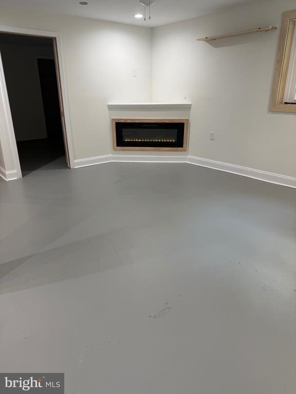  - unfurnished living room featuring a glass covered fireplace and baseboards