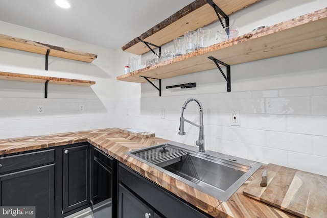  - kitchen featuring open shelves, butcher block countertops, dark cabinets, and tasteful backsplash