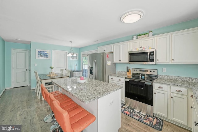 307 Cardinal, Louisa, VA 23093 - kitchen featuring appliances with stainless steel finishes, light wood-style flooring, a center island, and white cabinetry