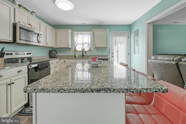 307 Cardinal, Louisa, VA 23093 - kitchen featuring appliances with stainless steel finishes, a kitchen island, a breakfast bar area, and light stone countertops