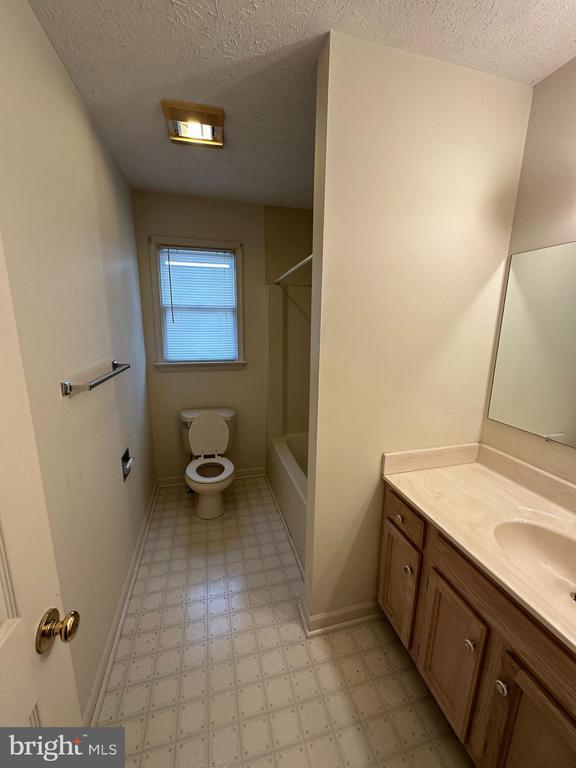 bathroom with tile patterned floors, a textured ceiling, vanity, baseboards, and toilet