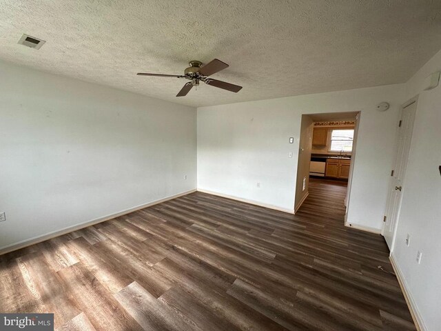 empty room with dark wood-type flooring, a sink, a ceiling fan, baseboards, and a textured ceiling