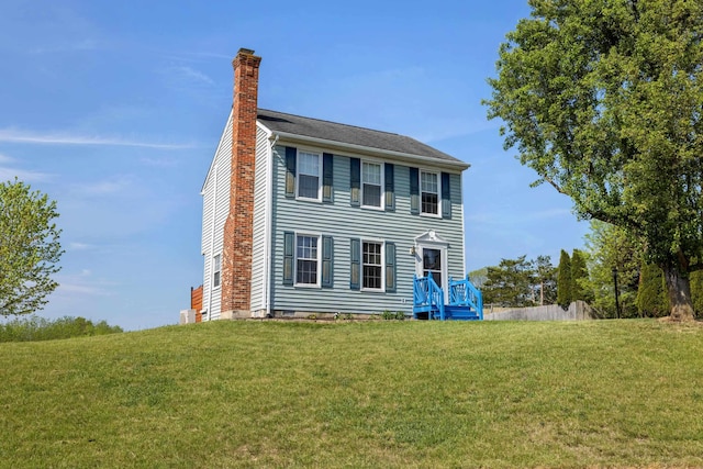 colonial-style house with a chimney and a front lawn