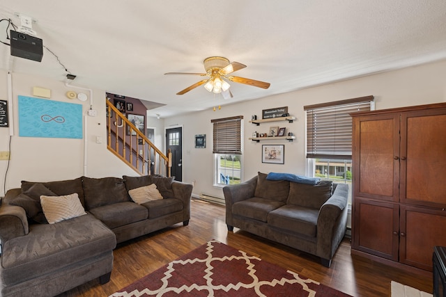 living room featuring a ceiling fan, stairway, dark wood finished floors, and a baseboard radiator