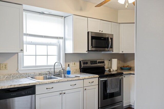 kitchen with appliances with stainless steel finishes, a sink, white cabinetry, and a ceiling fan