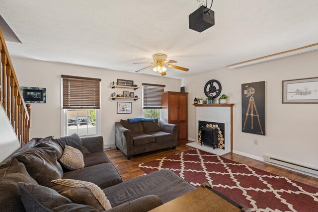 living room with a ceiling fan, a baseboard radiator, stairway, wood finished floors, and baseboards