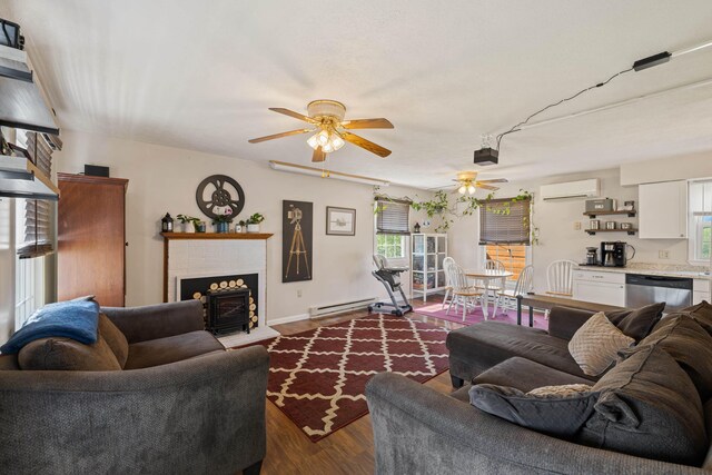 living room featuring a ceiling fan, a wall mounted AC, a baseboard radiator, a brick fireplace, and healthy amount of natural light