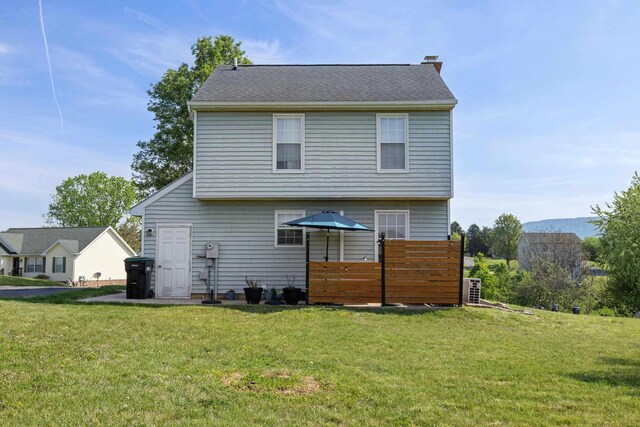 rear view of property with a chimney and a lawn