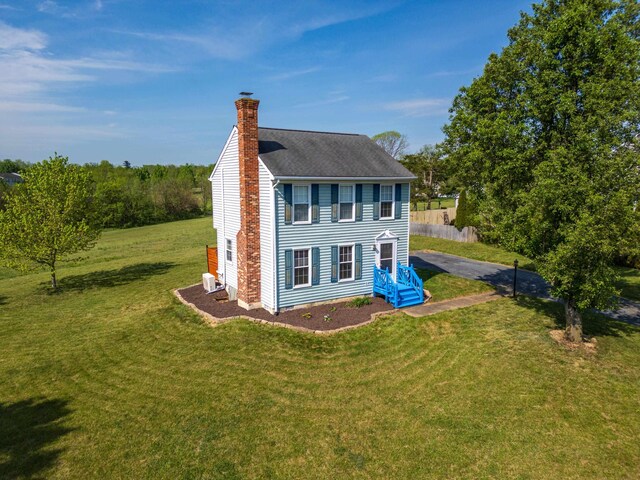 view of home's exterior with a chimney, a yard, and a shingled roof