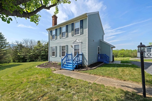 colonial inspired home with a chimney and a front lawn