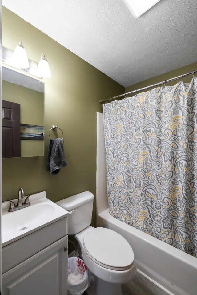 full bathroom featuring a textured ceiling, vanity, shower / bathtub combination with curtain, and toilet