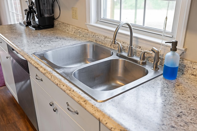kitchen view of a sink, dishwasher, and white cabinets