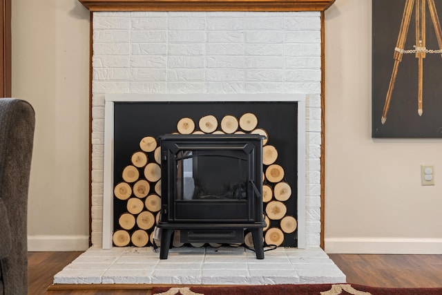 detailed view of baseboards, wood finished floors, and a wood stove