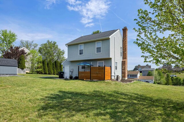 back of property with a chimney, an outbuilding, a storage unit, and central air condition unit