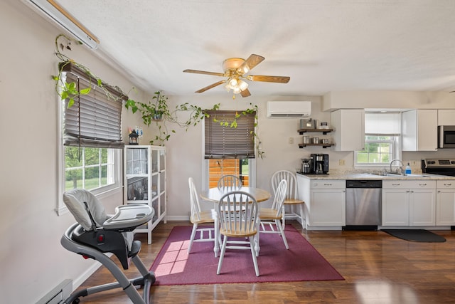 kitchen featuring appliances with stainless steel finishes, an AC wall unit, white cabinetry, and dark wood-style flooring