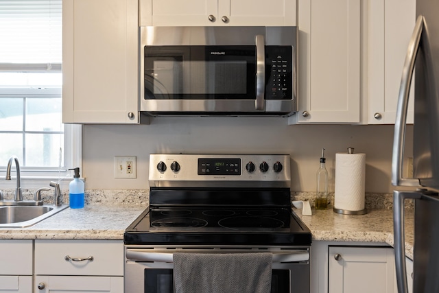 kitchen with stainless steel appliances, a sink, and white cabinetry
