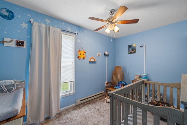 bedroom featuring a baseboard heating unit, carpet flooring, a nursery area, ceiling fan, and baseboards