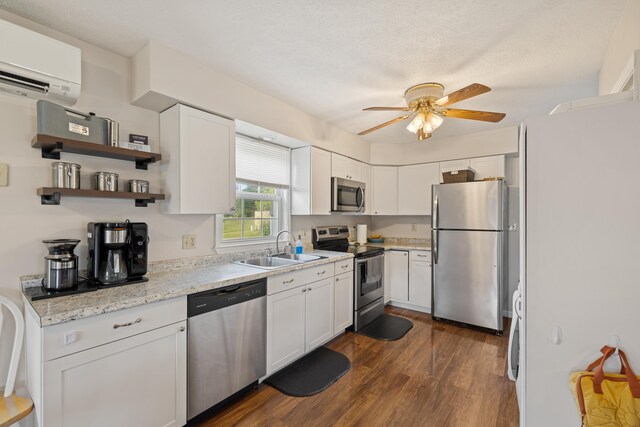 kitchen with stainless steel appliances, a wall unit AC, a sink, dark wood-style floors, and ceiling fan