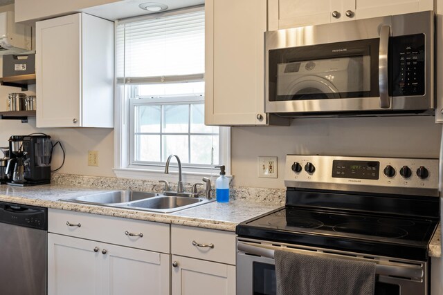 kitchen featuring appliances with stainless steel finishes, a sink, white cabinetry, and open shelves