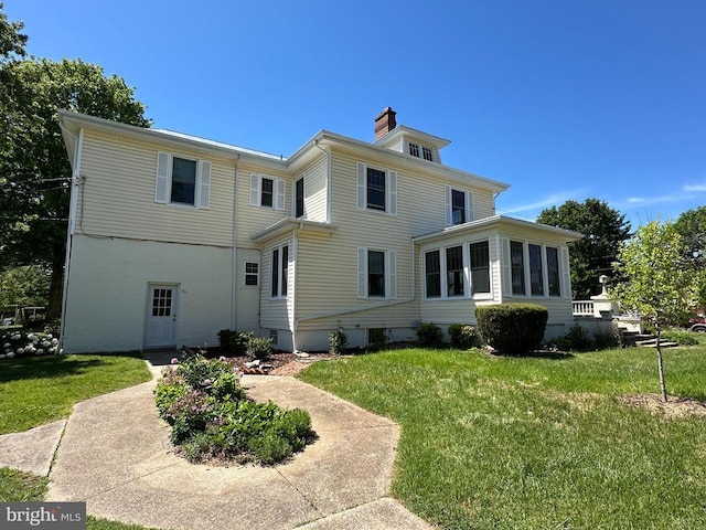 view of front of house with a chimney, a front lawn, and a sunroom