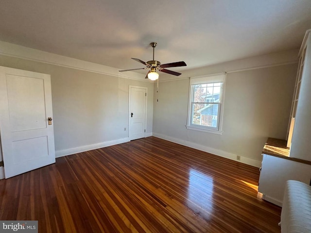 unfurnished bedroom featuring radiator, wood finished floors, baseboards, and ceiling fan