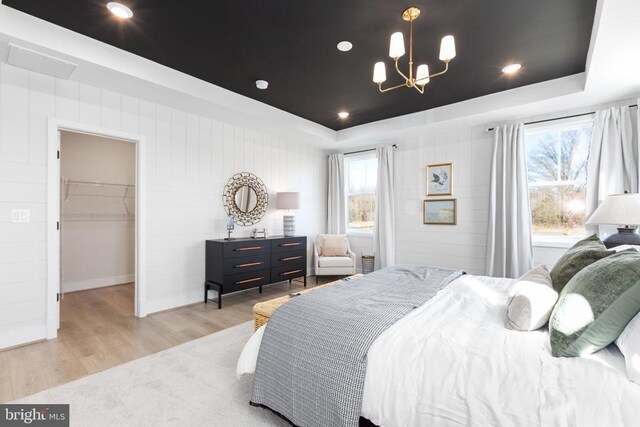10103 N Streamview Ct, Fredericksburg, VA 22408 - bedroom with a tray ceiling, light wood-style floors, a chandelier, a walk in closet, and baseboards